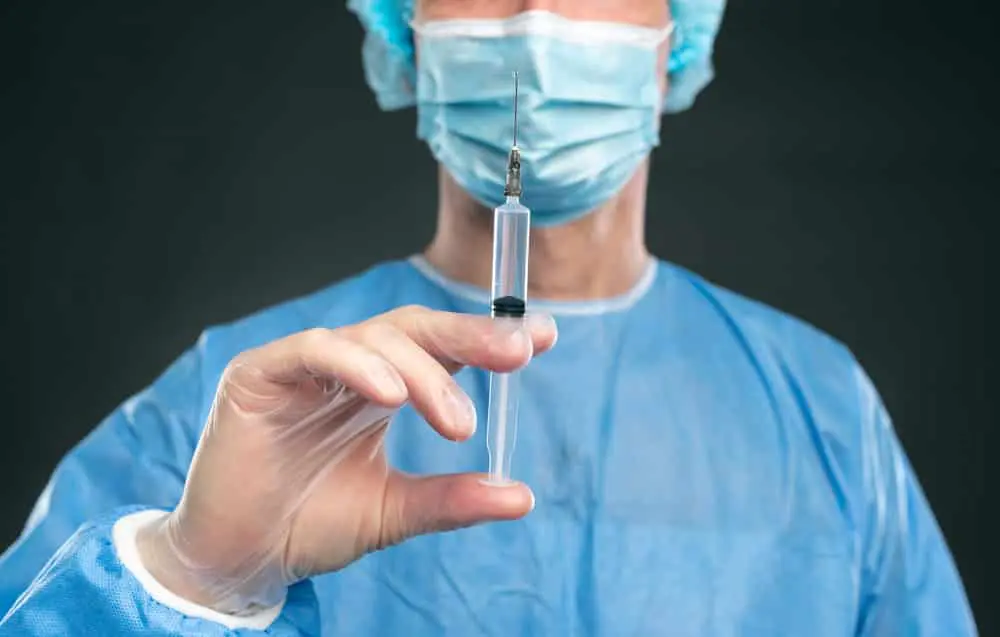 vaccine-syringe-held-by-doctor-wearing-face-mask