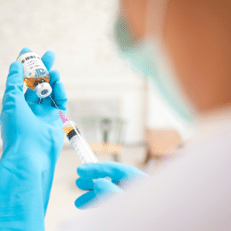Doctor filling syringe from a vial